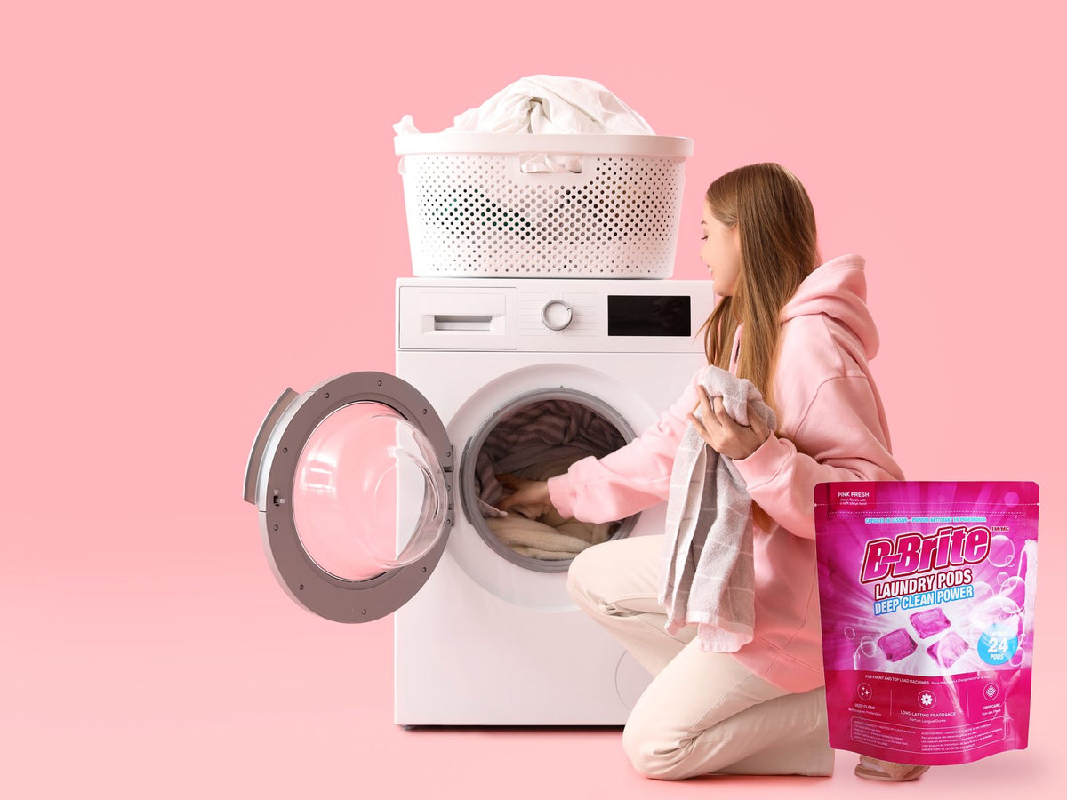 Woman loading a washing machine beside a bag of B-Brite Laundry Pods