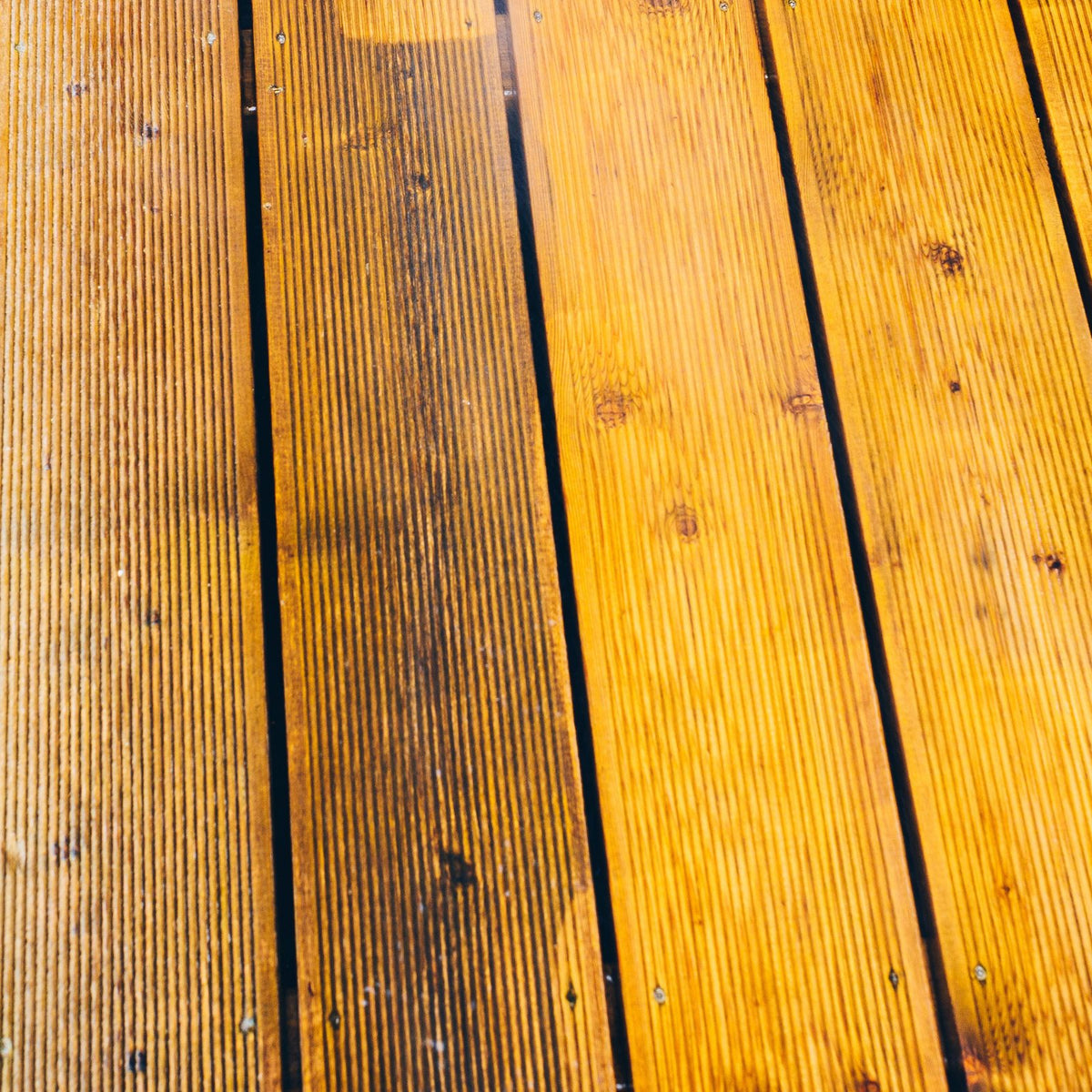 Weathered and restored wooden deck boards side by side